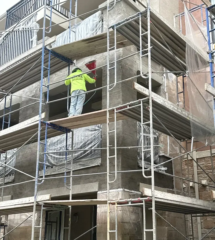 Worker applying material to an exterior wall from scaffolding