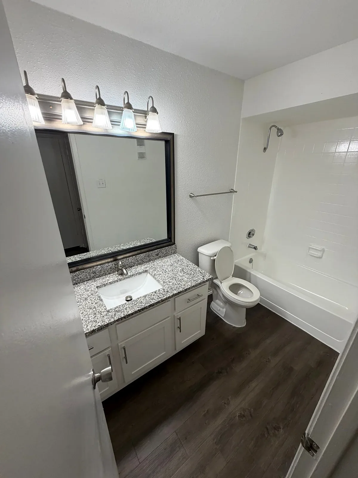 Apartment bathroom in Austin with a vanity, framed mirror, light fixtures and tub-shower.